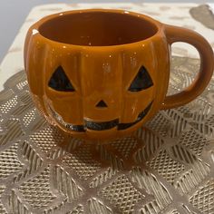 an orange coffee cup with a jack - o'- lantern face on it