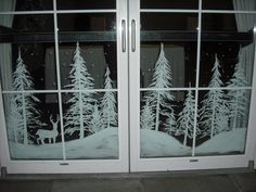 a window with frosted trees and a deer in the snow on it's side