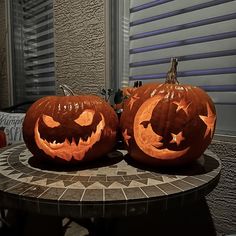 two carved pumpkins sitting on top of a table