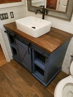 a white sink sitting on top of a wooden counter next to a toilet and mirror