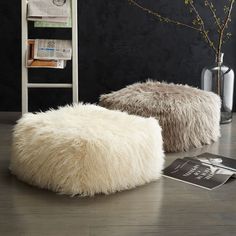 two white sheepskin pouffles sitting on top of a wooden floor next to a chair