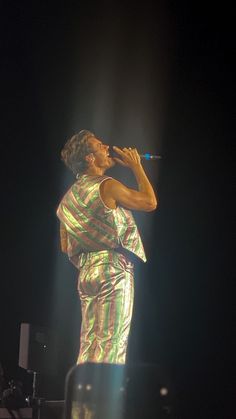 a man standing on top of a stage holding a microphone in his hand and singing