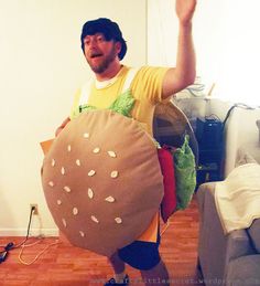 a man is dressed up as a hamburger and holding a giant burger bag in his hands