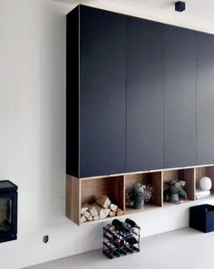 an empty room with black cabinets and white walls, including a firewood rack on the wall