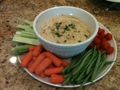 carrots, celery, and green beans are on a plate with dip