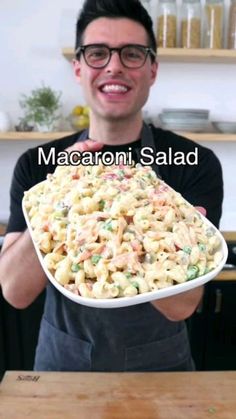 a man holding a plate full of macaroni salad