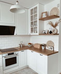 the kitchen is clean and ready for us to use it's white cabinets, wood counter tops, and appliances