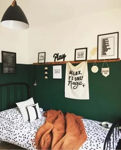 a bedroom with green walls and pictures hanging on the wall above the bedspread