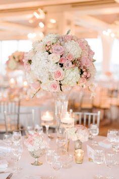 a vase filled with lots of white and pink flowers sitting on top of a table