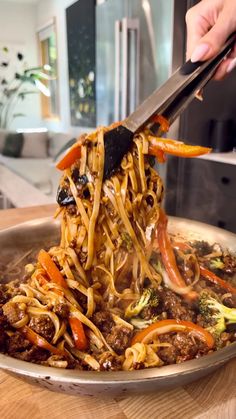 someone is chopping up some noodles in a pan