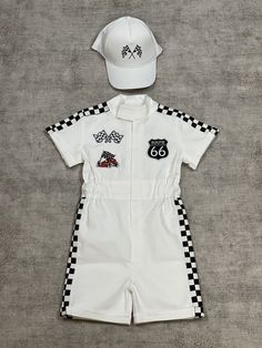 a white hat and overalls are laying on the floor next to a black and white checkered cap