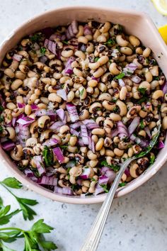 a bowl filled with beans and onions next to lemon wedges on a table top