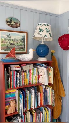 a bookshelf filled with lots of books next to a lamp and pictures on the wall