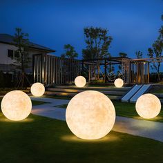 several large white balls are lit up on the grass