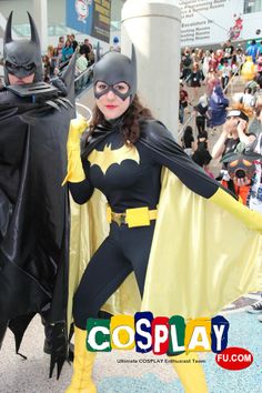 a woman in a batman costume standing next to a man wearing a bat suit and cape