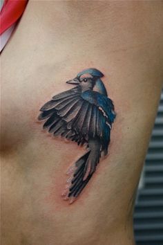 a blue bird tattoo on the side of a woman's stomach