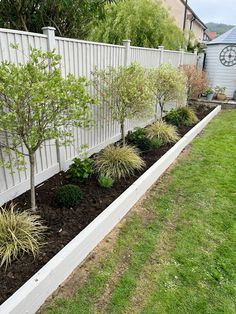 a white fence and some trees in a yard