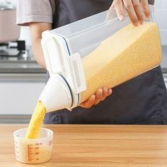 a person pouring batter into a bowl on top of a wooden table