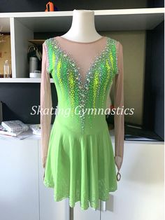 a green dress with sequins on it is displayed in front of a white cabinet