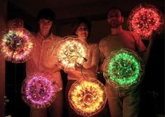 four people are holding lighted firework in the dark with their arms around each other