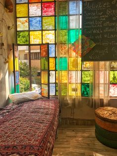 a bed sitting under a window covered in lots of colorful glass blocks next to a chalkboard