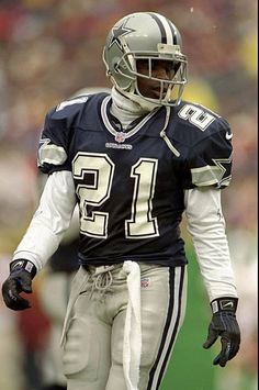 a football player is standing on the field with his hands in his pockets and wearing a helmet