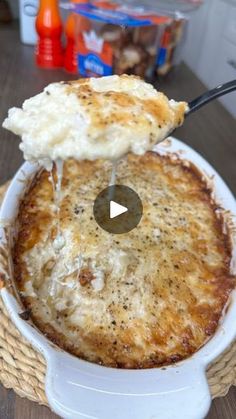 a bowl filled with cheese covered food on top of a wooden table