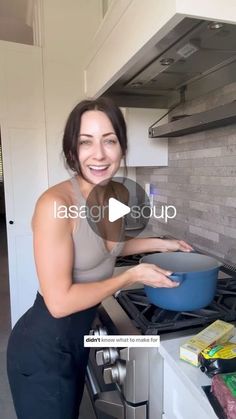 a woman is cooking in the kitchen with a blue bowl on her stove top and smiling at the camera