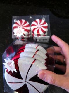 a hand is holding some candy canes in a clear box with red and white designs