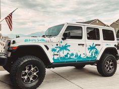 a white jeep with blue palm trees painted on it's side parked in front of a house