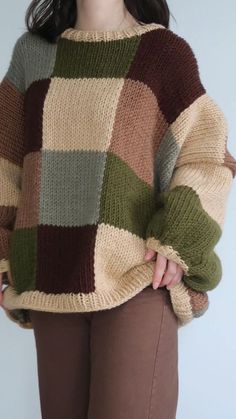 a woman is wearing a multicolored sweater and brown pants