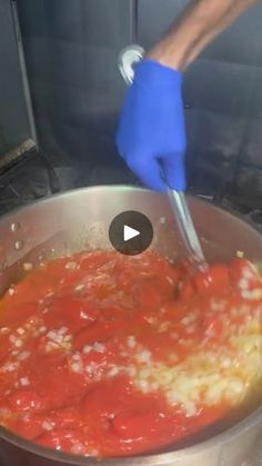 a person in blue gloves stirring food into a pot