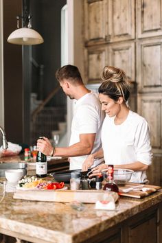 a man and woman are preparing food in the kitchen