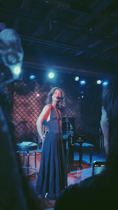 a woman standing in front of a microphone on stage