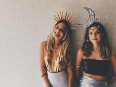 two women standing next to each other in front of a wall with the moon and stars on it