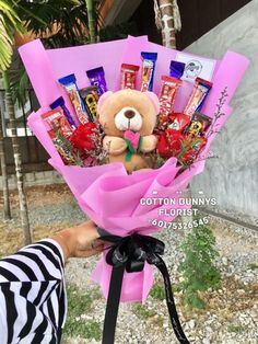 a person holding a teddy bear with candy bars in it