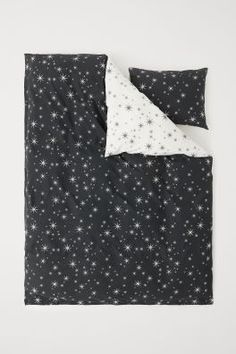 a black and white blanket with stars on it, next to an unmade pillow