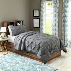 a bed sitting in a bedroom next to a window covered in blue and white curtains