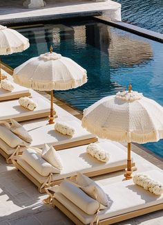 lounge chairs and umbrellas are lined up by the pool