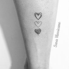 a small heart tattoo on the ankle with two smaller hearts in each other's hands