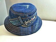 a denim hat with patches and buttons on the front is sitting on a white surface