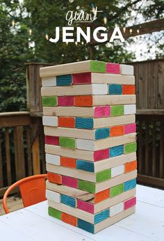 a wooden block tower sitting on top of a white table next to an orange chair