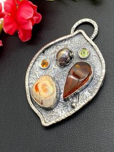 "Artisan Amber with Mexican Fire Opal pendant in sterling silver Hand-made Sterling Silver 925 Stones used: Baltic Amber, Mexican Fire Opal Purple Pearl, Peridot, Citrine Height - 2\", Width - 1 3/8\" Unique Handcrafted One-of a-kind Design Pendant Each Piece of Jewelry in my Collection is Absolutely One of a Kind! When you start wearing a piece of my jewelry you will fall in love with it more and more each day and feel that good Energy and Love that I pass into it while creating this piece of A Spiritual Sterling Silver Gemstone Pendant, Spiritual Sterling Silver Pendant Gemstone, Artisan Amber Sterling Silver Jewelry, Handmade Sterling Silver Oval Pendant Gemstone, Artisan Sterling Silver Cabochon Gemstones, Sterling Silver Cabochon Gemstones, Unique Sterling Silver Pendant Gemstones, Unique Teardrop Gemstone For Gift, Fusion Style Oval Sterling Silver Gemstones