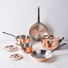 an assortment of pots and pans sitting on a white counter top next to each other