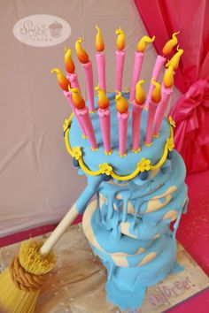 a blue cake with yellow candles on it and a broom sticking out of the top