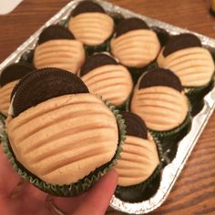 a hand holding a chocolate covered cupcake with peanut butter and oreo cookies on top