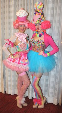 two women dressed in costumes standing next to each other on a wooden floor with curtains behind them