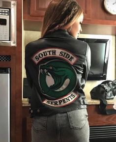 a woman standing in front of a refrigerator wearing a leather jacket with the words south side serpents on it