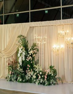 a wedding stage with flowers and chandelier hanging from it's side wall