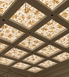 the ceiling is decorated with gold flowers and leaves on white walls, along with glass windows